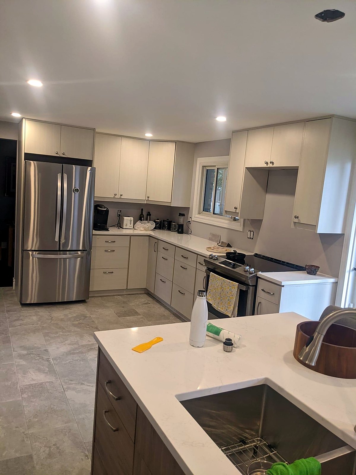 Kitchen after renovation — white cabinetry, quartz counters and stainless appliances